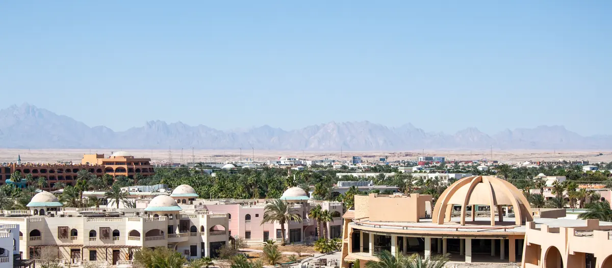 Homes and palm trees in a desert resort town, with mountains behind