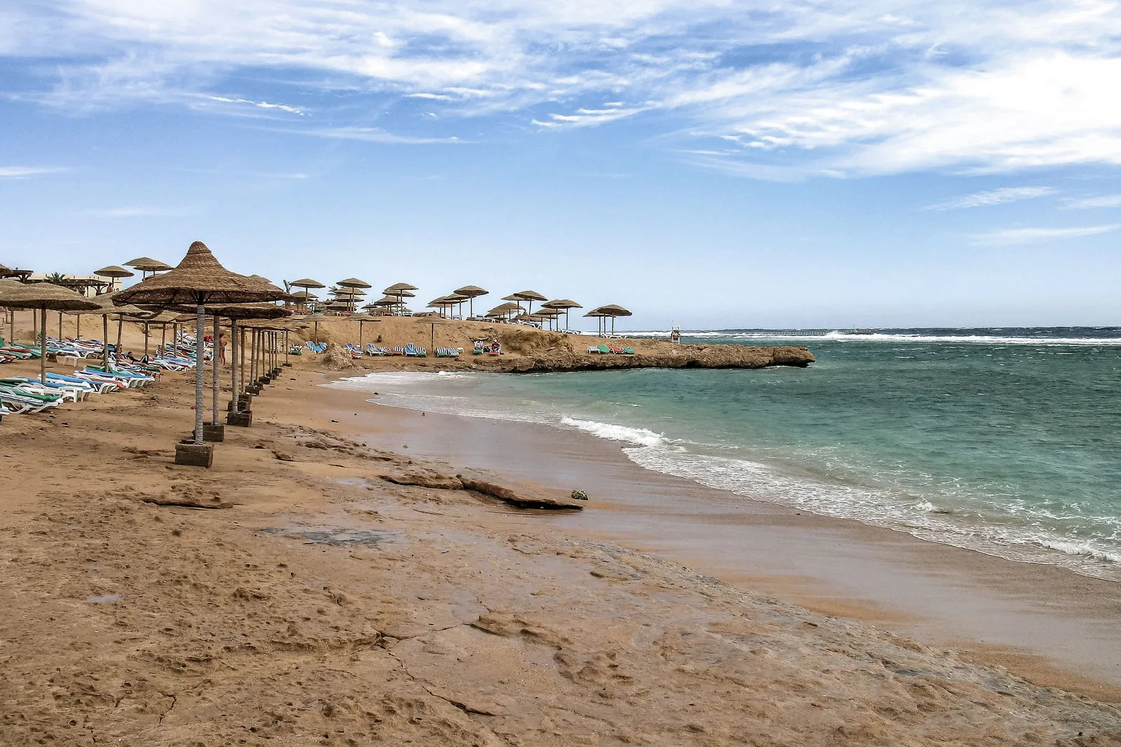 A quiet sandy beach with straw parasols on the Red Sea in Sharm El Sheikh